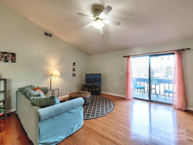 living room with wood finished floors, visible vents, ceiling fan, vaulted ceiling, and a textured ceiling