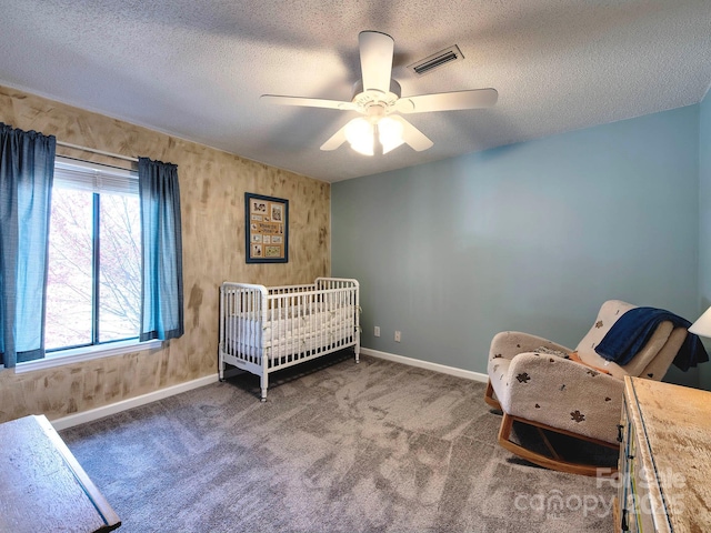 unfurnished bedroom with a ceiling fan, baseboards, visible vents, a textured ceiling, and carpet flooring