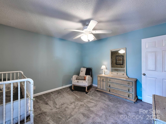 carpeted bedroom featuring a textured ceiling, a nursery area, baseboards, and ceiling fan