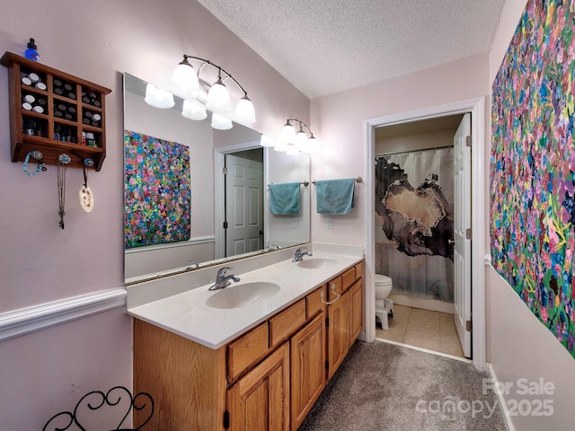 bathroom featuring a textured ceiling, double vanity, toilet, and a sink