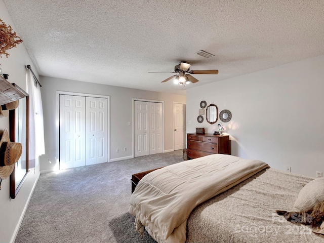 bedroom featuring visible vents, two closets, a ceiling fan, carpet flooring, and baseboards