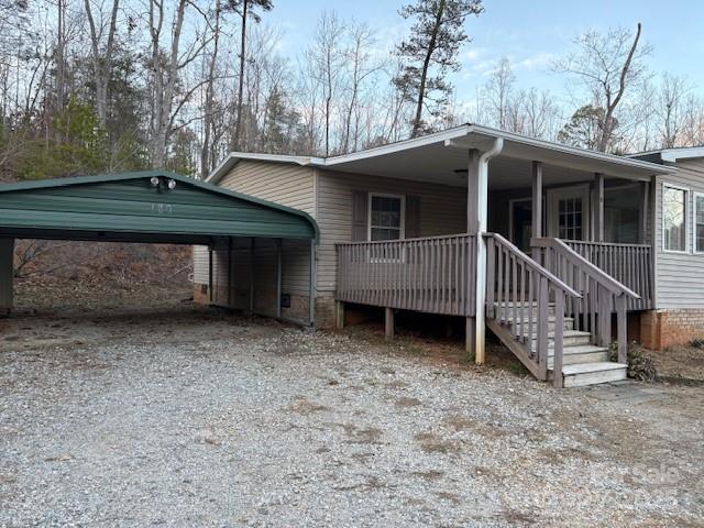 view of property exterior with a detached carport, a porch, and gravel driveway