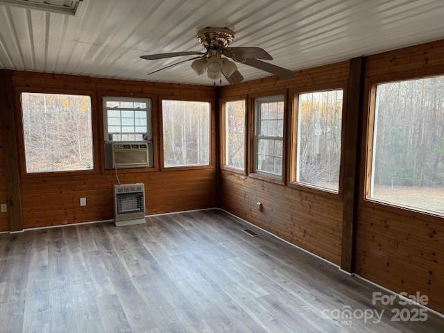 unfurnished sunroom featuring cooling unit, heating unit, visible vents, and ceiling fan