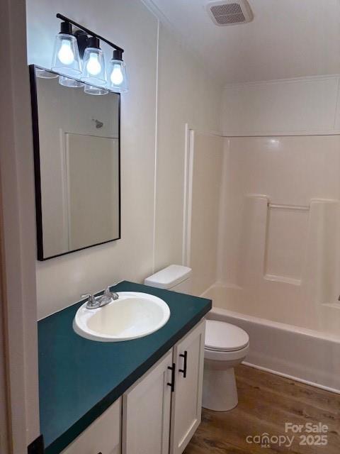 bathroom featuring visible vents, toilet, wood finished floors, vanity, and  shower combination