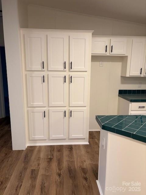 kitchen with white cabinetry, tile counters, dark wood finished floors, and ornamental molding