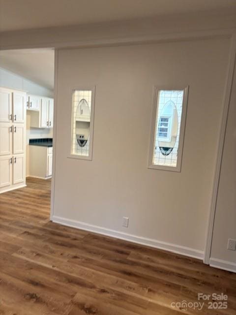 spare room with baseboards and dark wood-style flooring