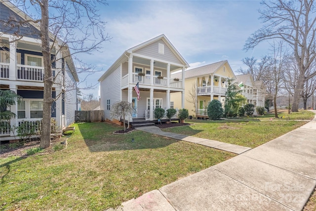view of front of property with a balcony, a porch, a front lawn, and fence
