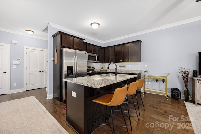 kitchen with light stone counters, dark wood-style flooring, a sink, stainless steel appliances, and dark brown cabinets