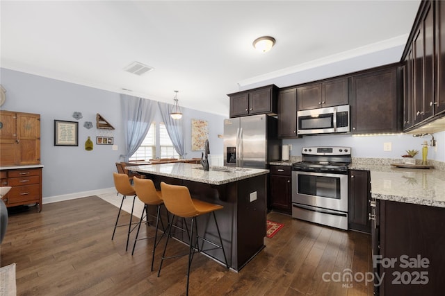 kitchen with visible vents, light stone countertops, a breakfast bar area, appliances with stainless steel finishes, and dark wood-style floors