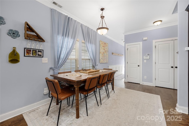 dining area featuring visible vents, crown molding, baseboards, and wood finished floors