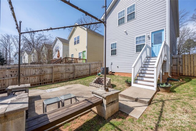 rear view of house with cooling unit, a patio, a yard, and a fenced backyard