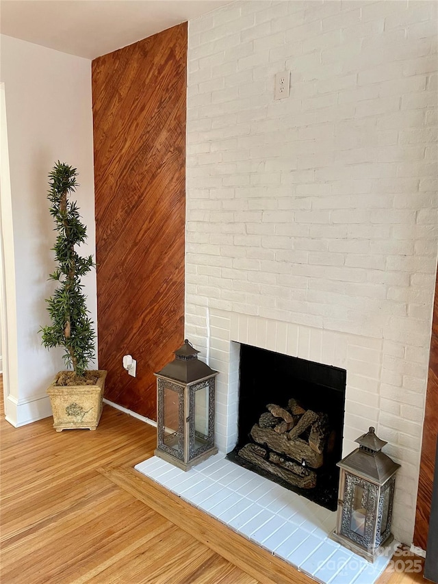 room details with baseboards, a brick fireplace, and wood finished floors