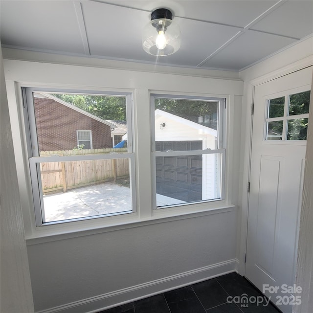 interior space with dark tile patterned flooring, baseboards, and a wealth of natural light