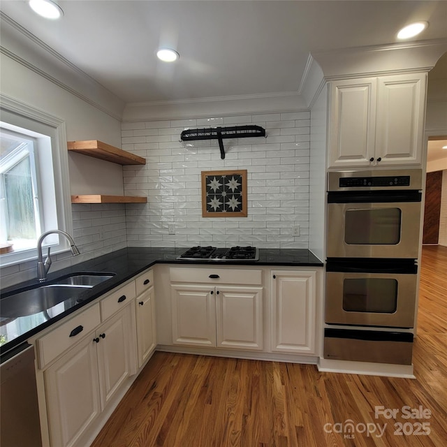 kitchen with a warming drawer, ornamental molding, a sink, open shelves, and appliances with stainless steel finishes