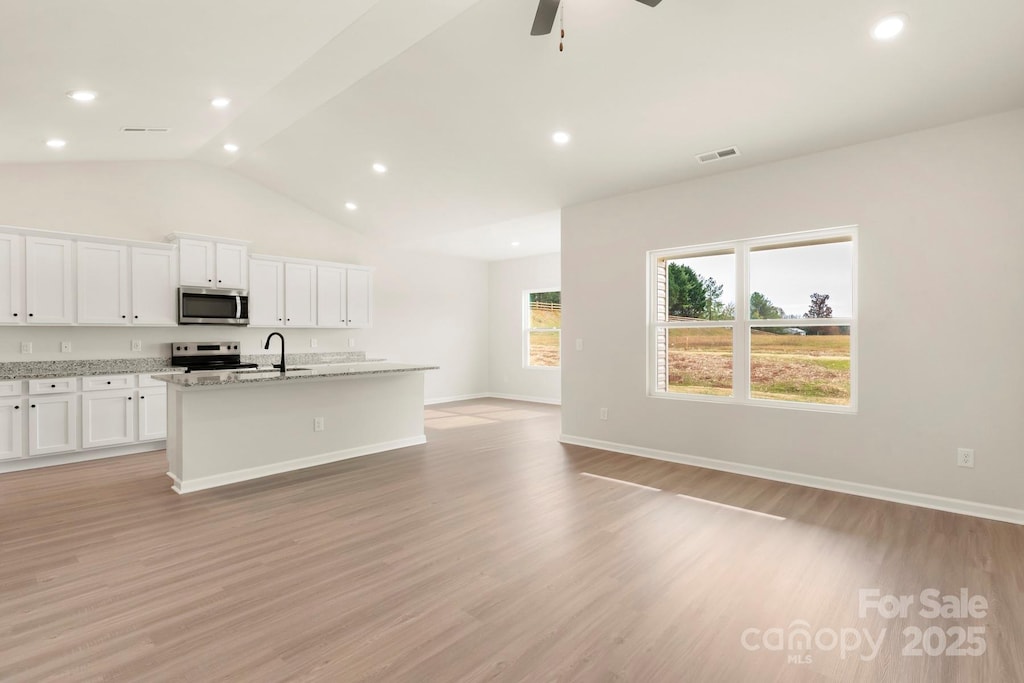 kitchen with stainless steel appliances, visible vents, a center island with sink, and light wood finished floors
