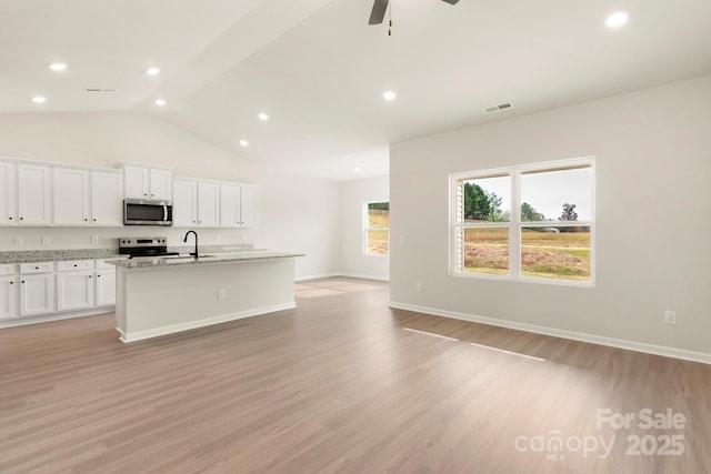 kitchen with stainless steel appliances, visible vents, a center island with sink, and light wood finished floors