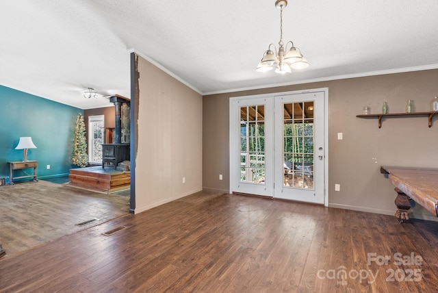 unfurnished living room featuring a wood stove, plenty of natural light, wood-type flooring, and a chandelier