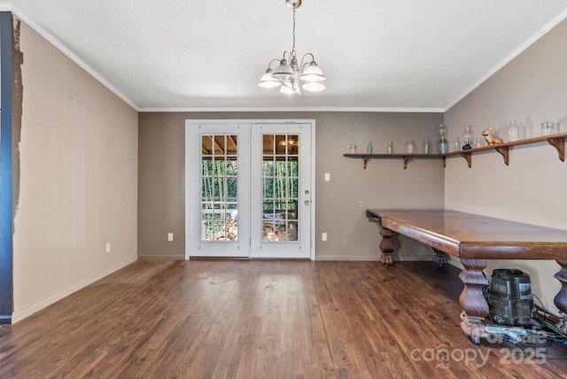 unfurnished dining area featuring crown molding, wood finished floors, baseboards, and a chandelier