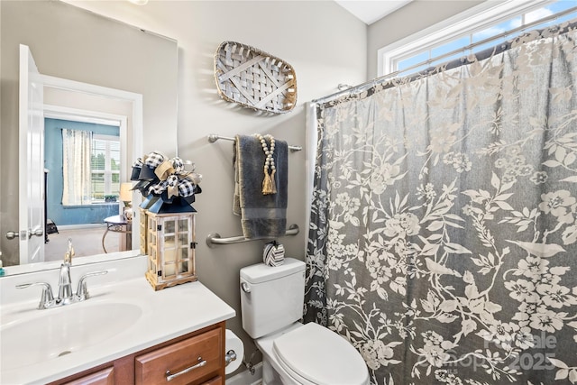 bathroom featuring toilet, vanity, a shower with curtain, and a healthy amount of sunlight