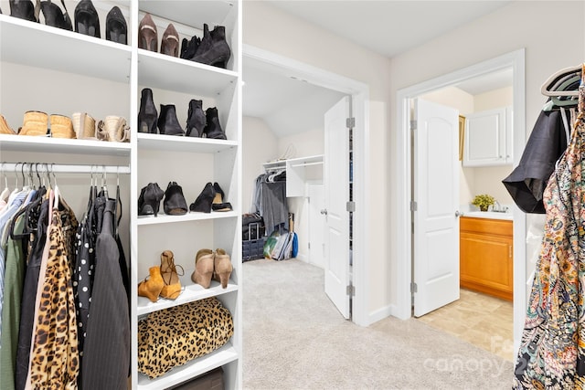 spacious closet featuring light colored carpet and vaulted ceiling