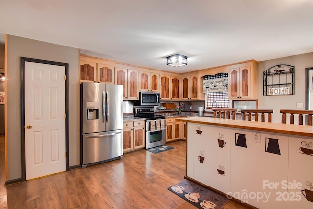 kitchen with stainless steel appliances, wooden counters, wood finished floors, and light brown cabinetry