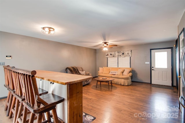 kitchen with ceiling fan, a breakfast bar area, wood finished floors, and butcher block counters