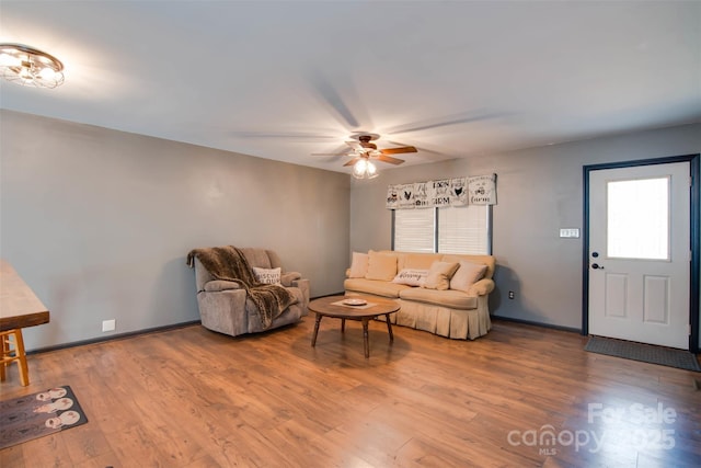 living room featuring ceiling fan, baseboards, and wood finished floors