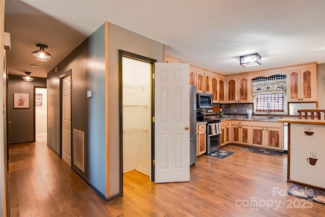 kitchen featuring stainless steel appliances, visible vents, light wood-style flooring, and light brown cabinets