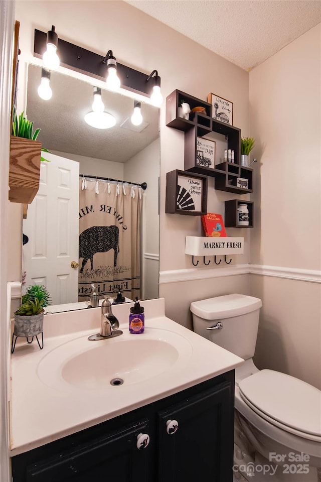 full bath with vanity, toilet, and a textured ceiling