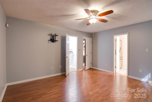 interior space with a ceiling fan, ensuite bathroom, a textured ceiling, wood finished floors, and baseboards