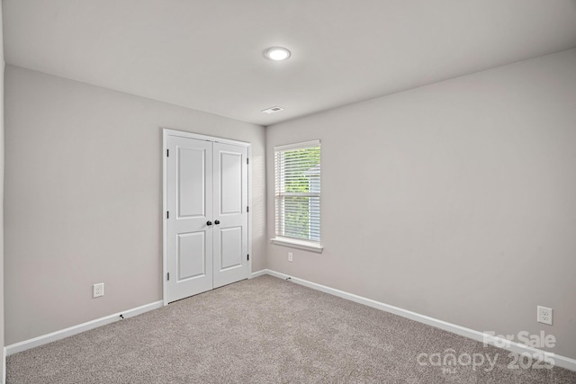 unfurnished bedroom featuring carpet, baseboards, and a closet