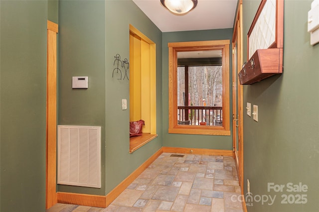 hall with visible vents, stone finish flooring, and baseboards