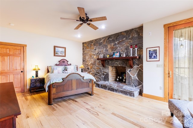 bedroom with a fireplace, wood finished floors, baseboards, and ceiling fan