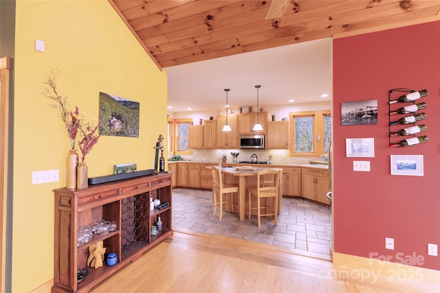 kitchen with stainless steel microwave, light brown cabinets, a kitchen island, light countertops, and a kitchen breakfast bar