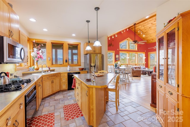 kitchen with black appliances, a sink, tasteful backsplash, stone tile floors, and a breakfast bar area