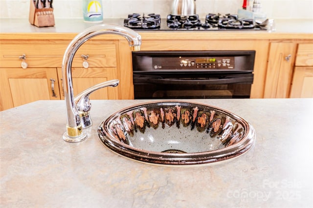 room details with black oven, gas stovetop, and a sink