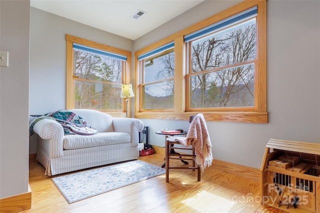 living area with wood finished floors, visible vents, and baseboards