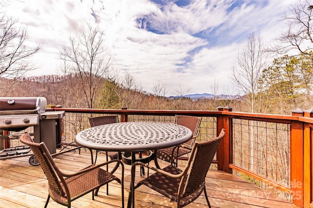 wooden terrace with grilling area, a mountain view, a view of trees, and outdoor dining area