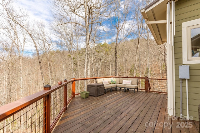 wooden terrace with a wooded view and outdoor lounge area