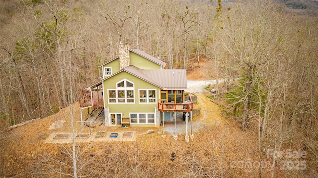 back of property with a deck, metal roof, and a chimney