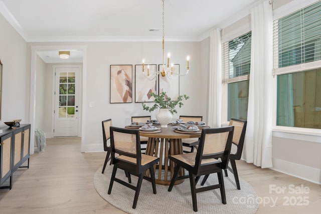 dining space with visible vents, baseboards, light wood finished floors, crown molding, and a notable chandelier