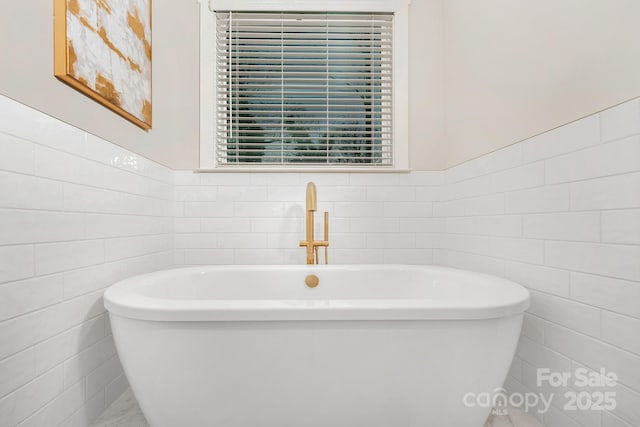 full bathroom with tile walls and a freestanding tub