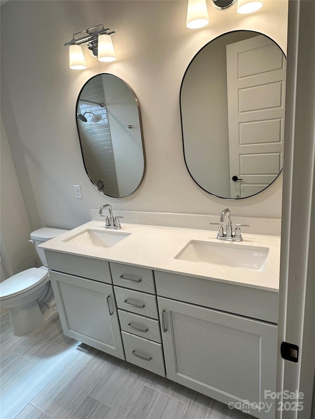 full bath with double vanity, toilet, and a sink