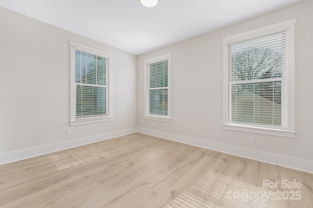 spare room with light wood-style flooring, a healthy amount of sunlight, and baseboards