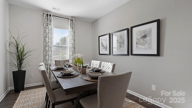 dining area featuring visible vents, baseboards, and dark wood-style floors