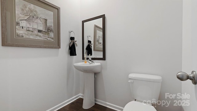 bathroom with toilet, wood finished floors, and baseboards