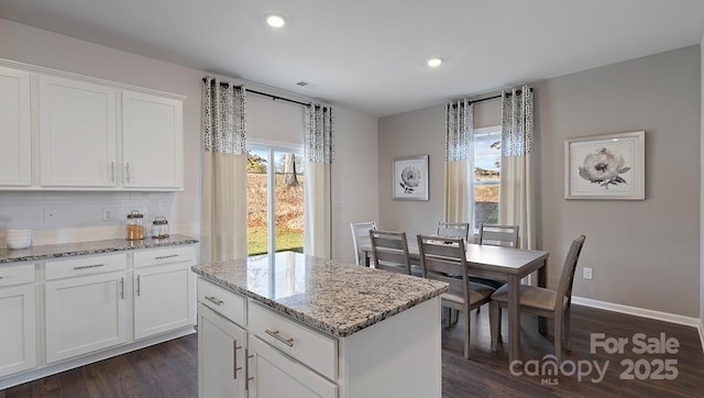 kitchen with dark wood-type flooring, tasteful backsplash, a kitchen island, recessed lighting, and light stone countertops