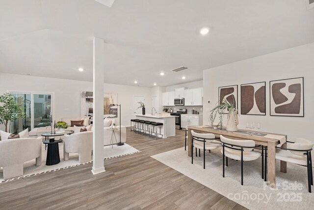 dining space with light wood-type flooring, visible vents, and recessed lighting