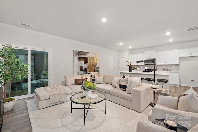 living room with light wood finished floors, visible vents, and recessed lighting