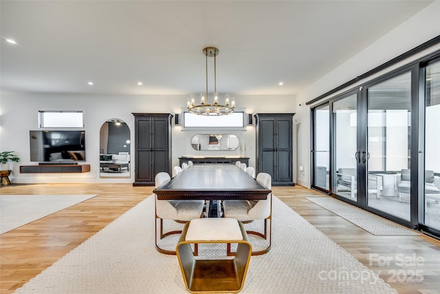 dining area with recessed lighting, arched walkways, a chandelier, and light wood-style floors